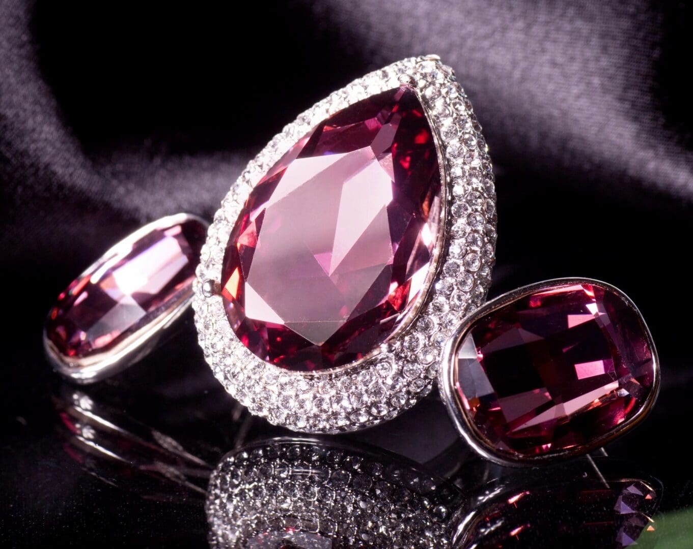 A large diamond ring and earrings on top of a black cloth.